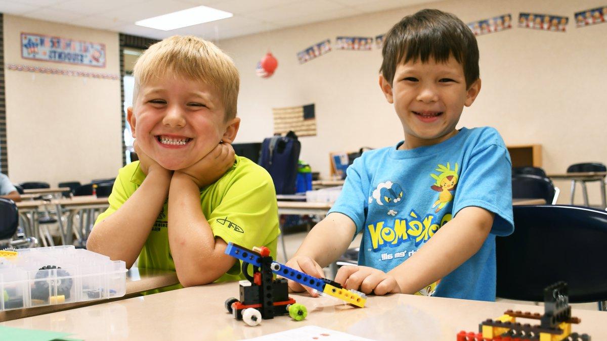 Two students smile while working with Legos at a desk